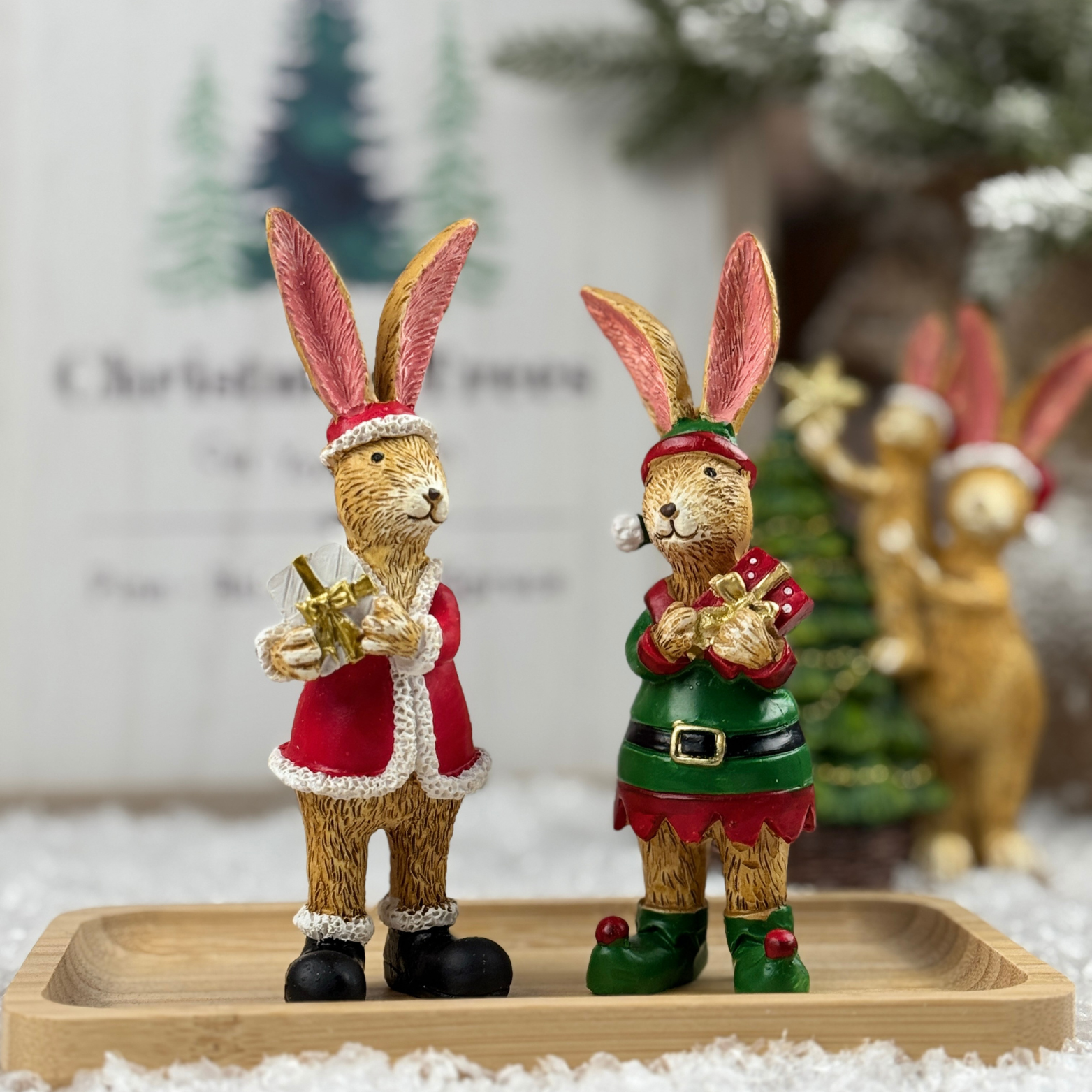 Two decorative rabbit figurines in festive outfits one as Santa and the other as an elf.
