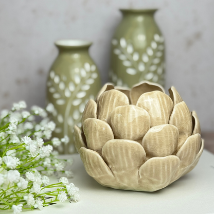artichoke tea light holder with green bottle vases in the background