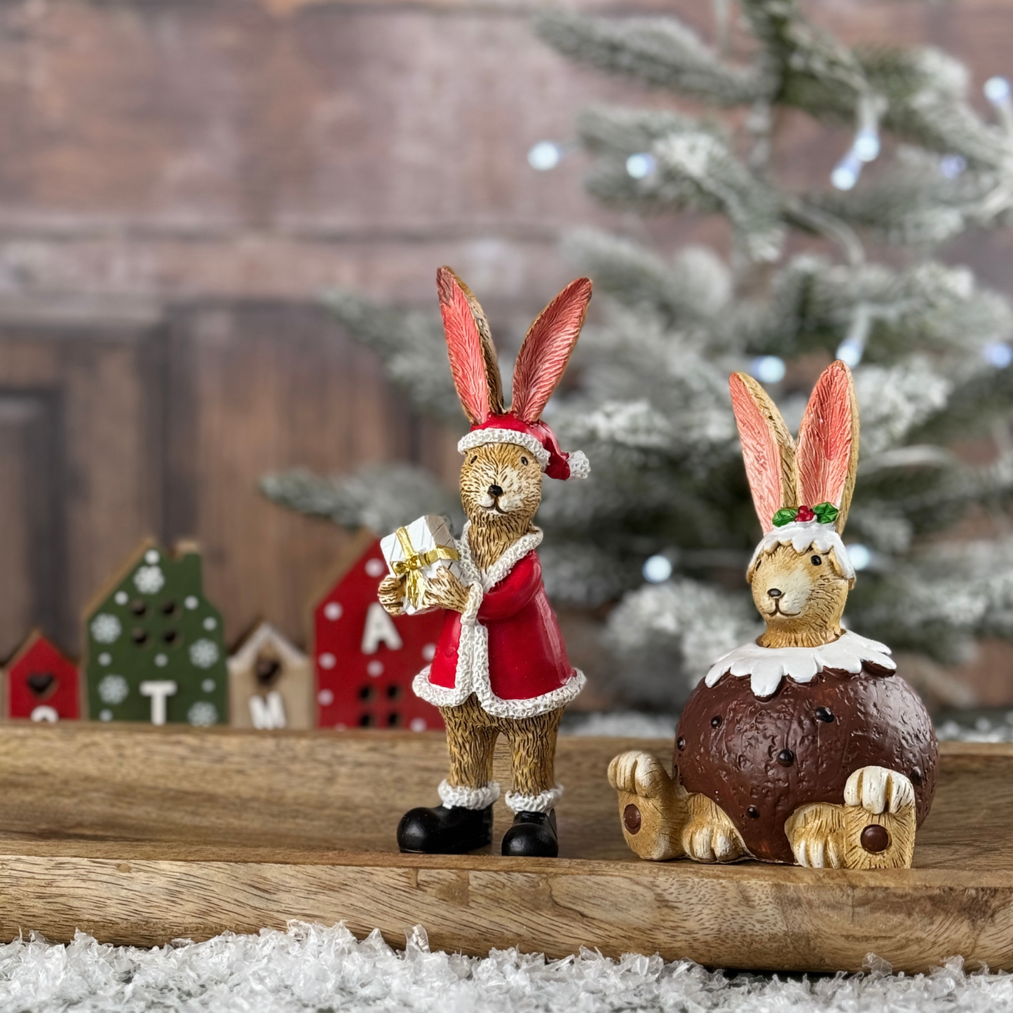 christmas bunnies one in a santa costume and the other sat in a christmas pudding