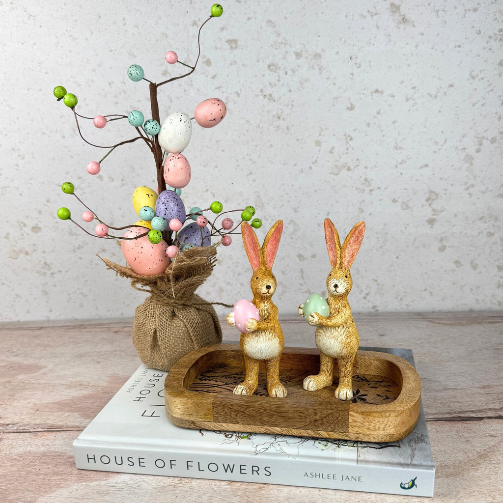 bunnies with pink or green egg with easter tree with pastel eggs