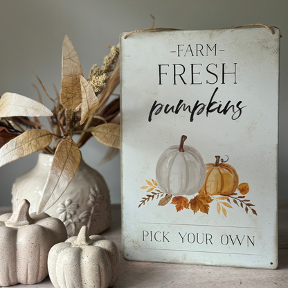 Decorative sign with 'Farm Fresh Pumpkins' text and pumpkin illustrations, surrounded by ceramic pumpkins and leaves.