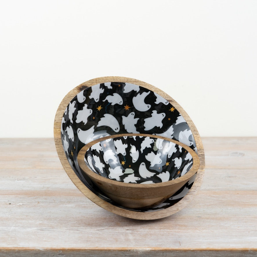 Wooden bowl with black interior featuring white ghost patterns on a wooden surface.