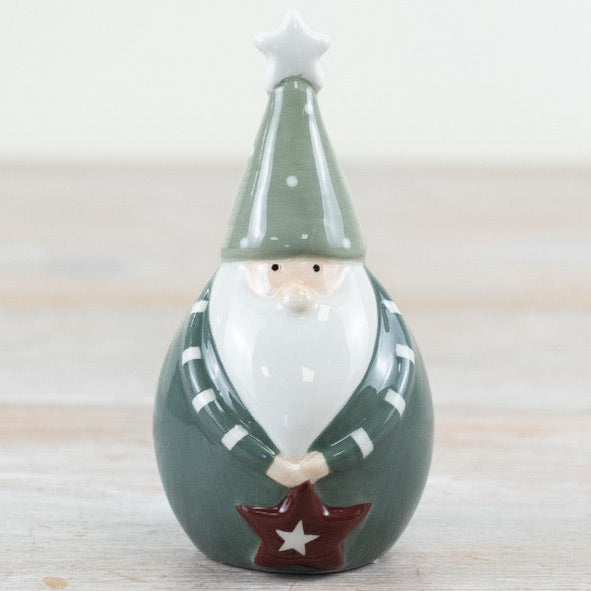 Decorative santa figurine with a green hat and star on a wooden surface