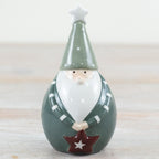 Decorative santa figurine with a green hat and star on a wooden surface