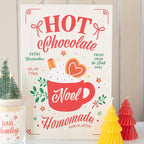 Decorative sign with 'Hot Chocolate Noel' design, surrounded by small Christmas trees and a candle.