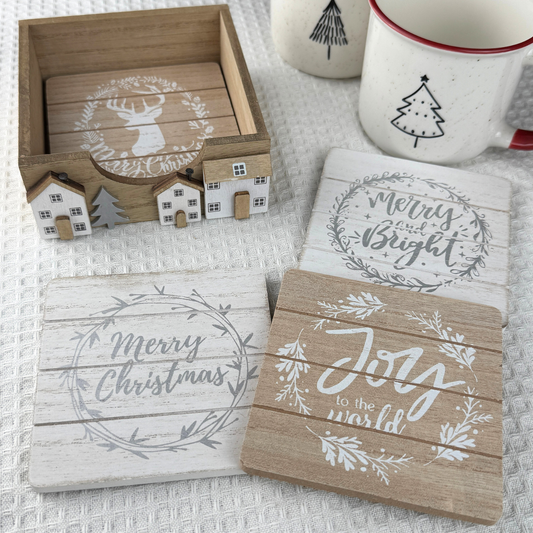 set of 4 christmas coasters presented in a wooden holder with festive houses on the front