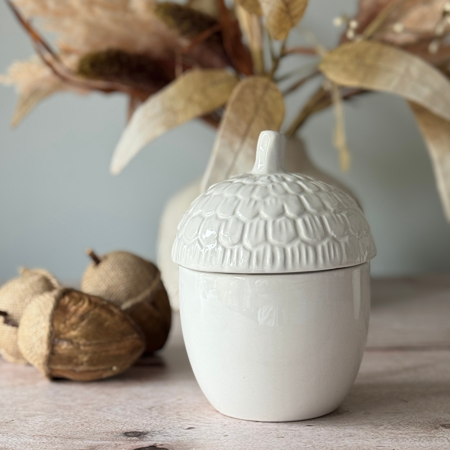 White textured ceramic jar with lid on a wooden surface with decorative elements.
