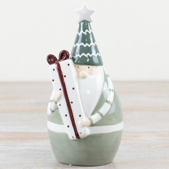 Decorative ceramic figure of a santa with a green hat and white beard on a wooden surface.