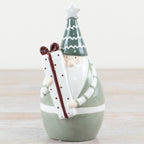Decorative ceramic figure of a santa with a green hat and white beard on a wooden surface.