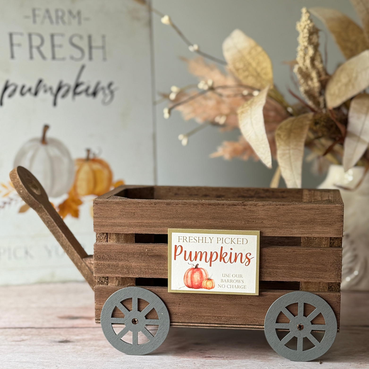 Wooden cart with 'Freshly Picked Pumpkins' sign in a decorative setting