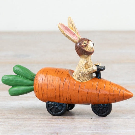 rabbit driving a carrot car on a wooden surface