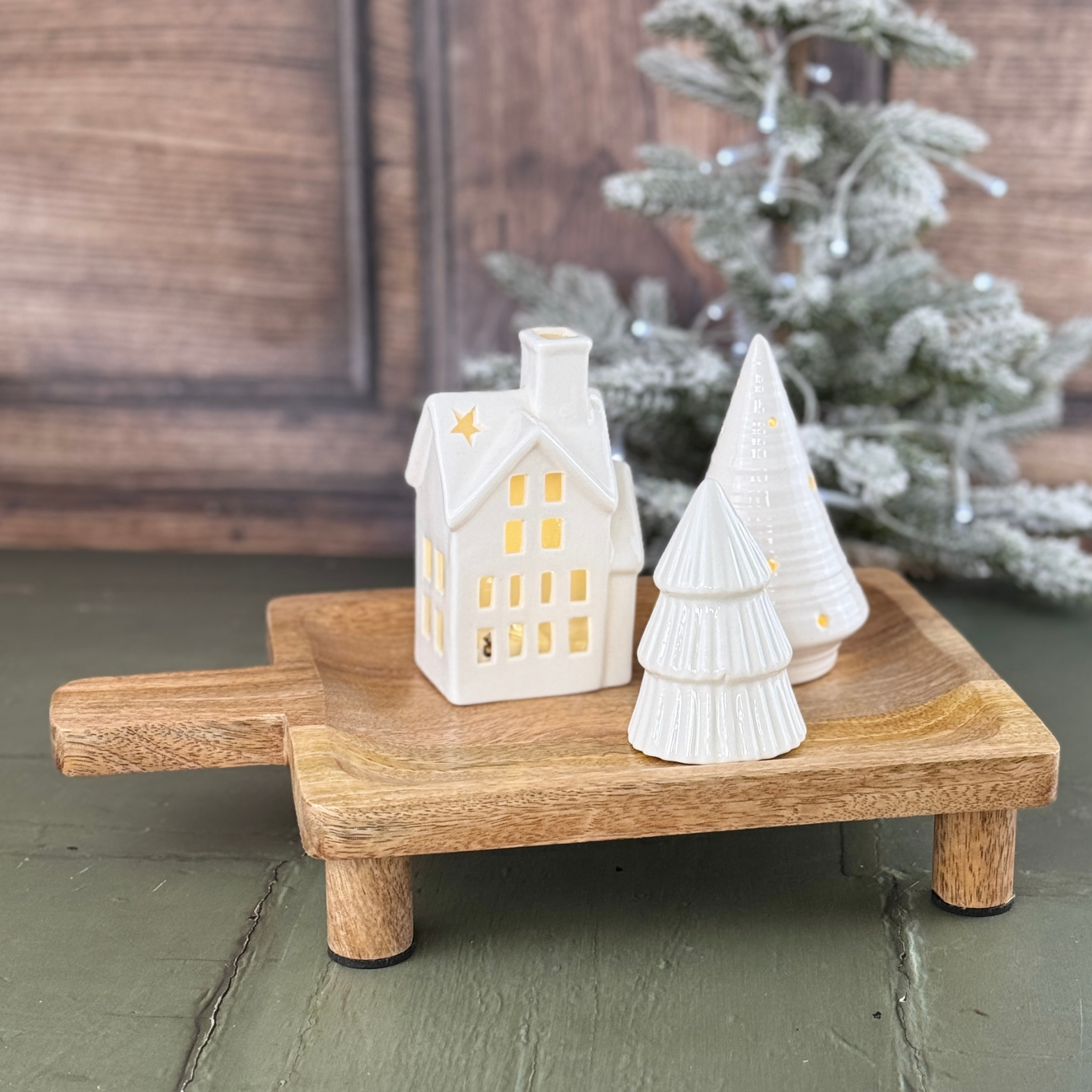 small rectangular board with light up house and ceramic tree