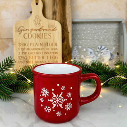 Red mug with a white snowflake pattern styled in a kitchen with chopping boards