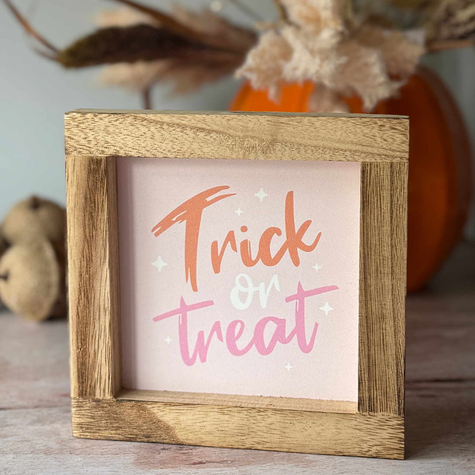 wooden sign with trick or treat in soft orange and pink