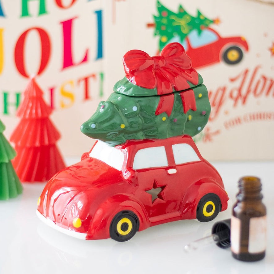 Decorative car with a Christmas tree on top, set against a festive background with colorful letters and a red car.
